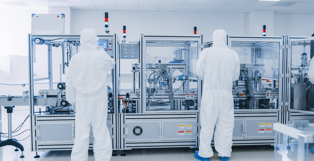 Operators in cleanroom overalls working high-precision industrial 3D printers within a manufacturing plant.