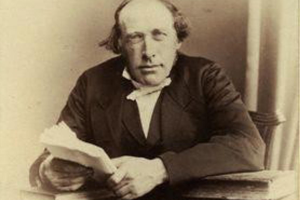 A sepia photographic portrait of the Scottish physicist and theologian Reverend John Kerr (1824–1907), discoverer of the electro-optic effect, depicted as a distinguished Victorian gentleman with a full beard, wearing a formal dark coat and white collar