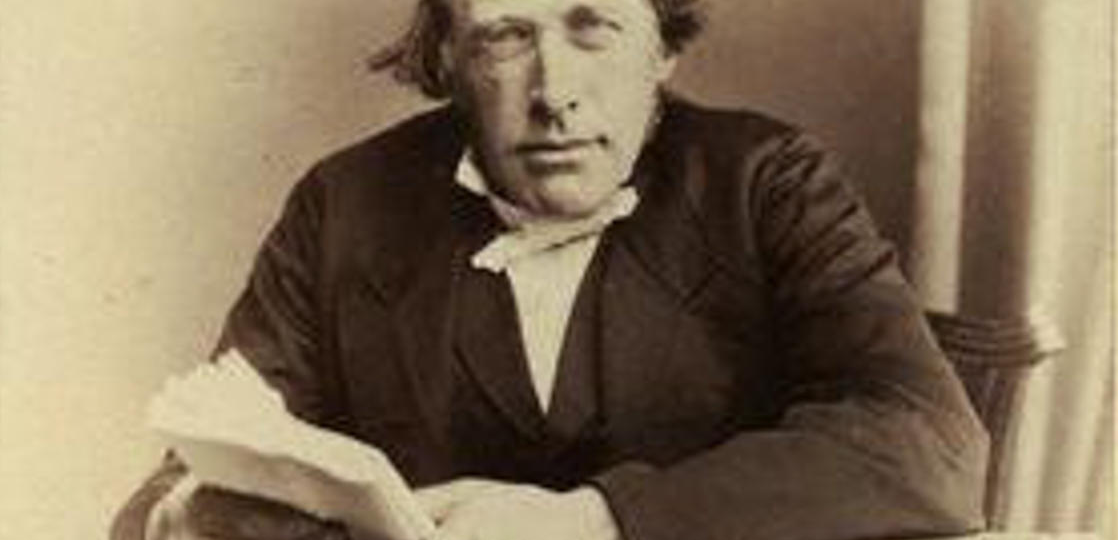 A sepia photographic portrait of the Scottish physicist and theologian Reverend John Kerr (1824–1907), discoverer of the electro-optic effect, depicted as a distinguished Victorian gentleman with a full beard, wearing a formal dark coat and white collar